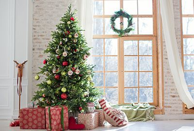 Geschmückter Weihnachtsbaum mit Geschenken vor einem Fenster